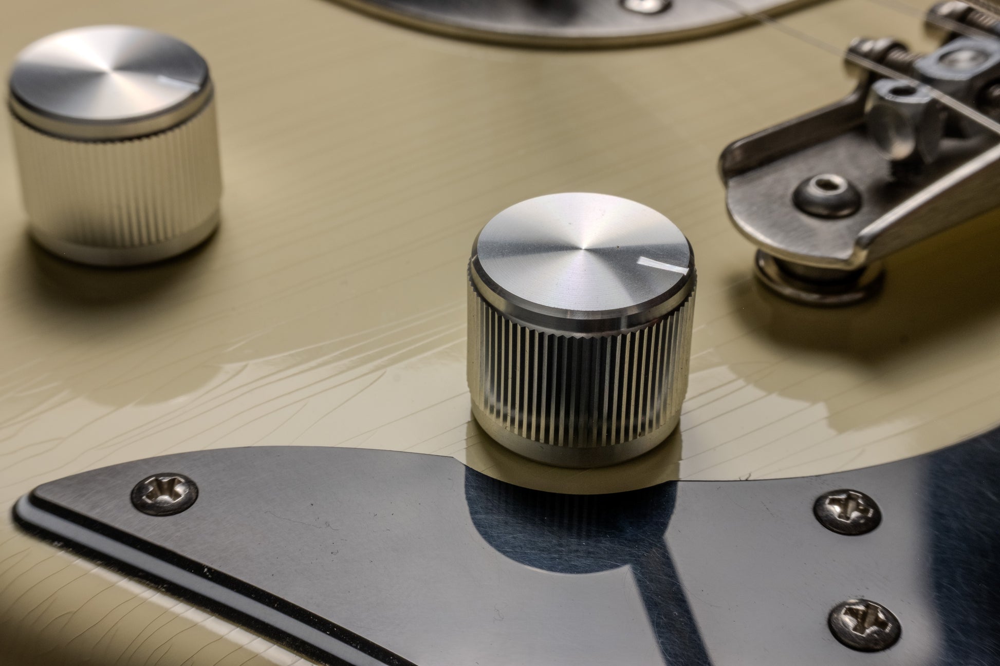 Close-up of a guitar's control knobs and bridge